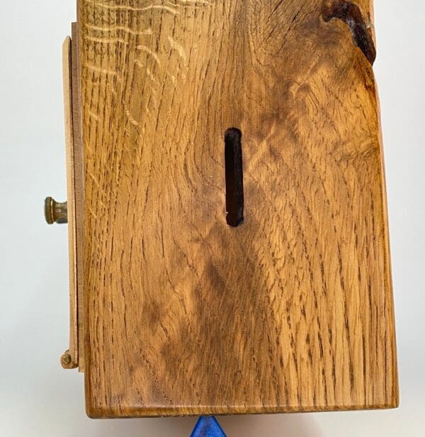 A wooden box with a blue handle and a slot in it.