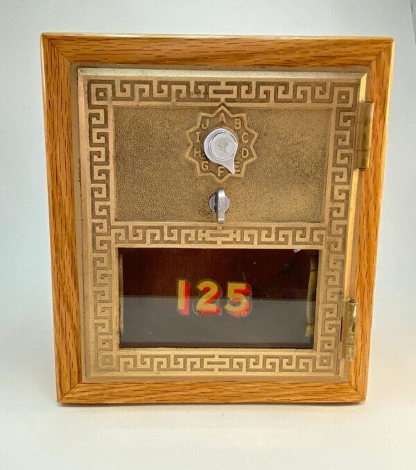 A wooden box with a gold frame and a key.