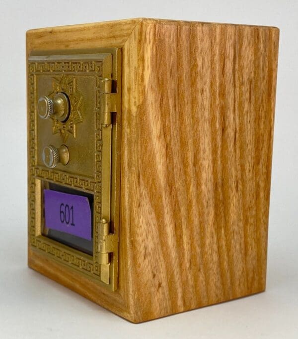 A wooden box with a gold door and purple metal plaque.