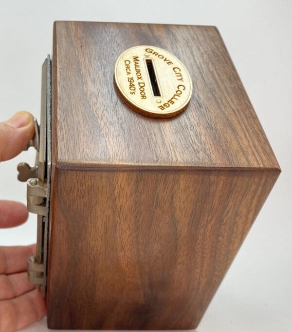 A hand is holding onto the top of a wooden box.