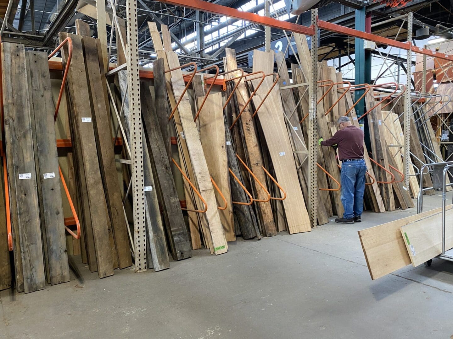 A man is looking at wood in an industrial warehouse.