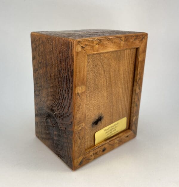 Wooden block with engraved label on base.